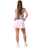 A woman wearing a pink Sofibella Women's UV Colors 14" Skort and a multicolour tank top on a white background.