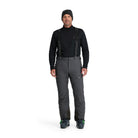 A man wearing a pair of grey Spyder Men's Dare Ski Pants that are waterproof, insulated, breathable, and stretchable.