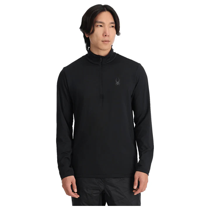 A man wearing a black Spyder Men's Prospect Turtleneck midlayer sweater that is breathable, strechable, and moisture-wicking.
