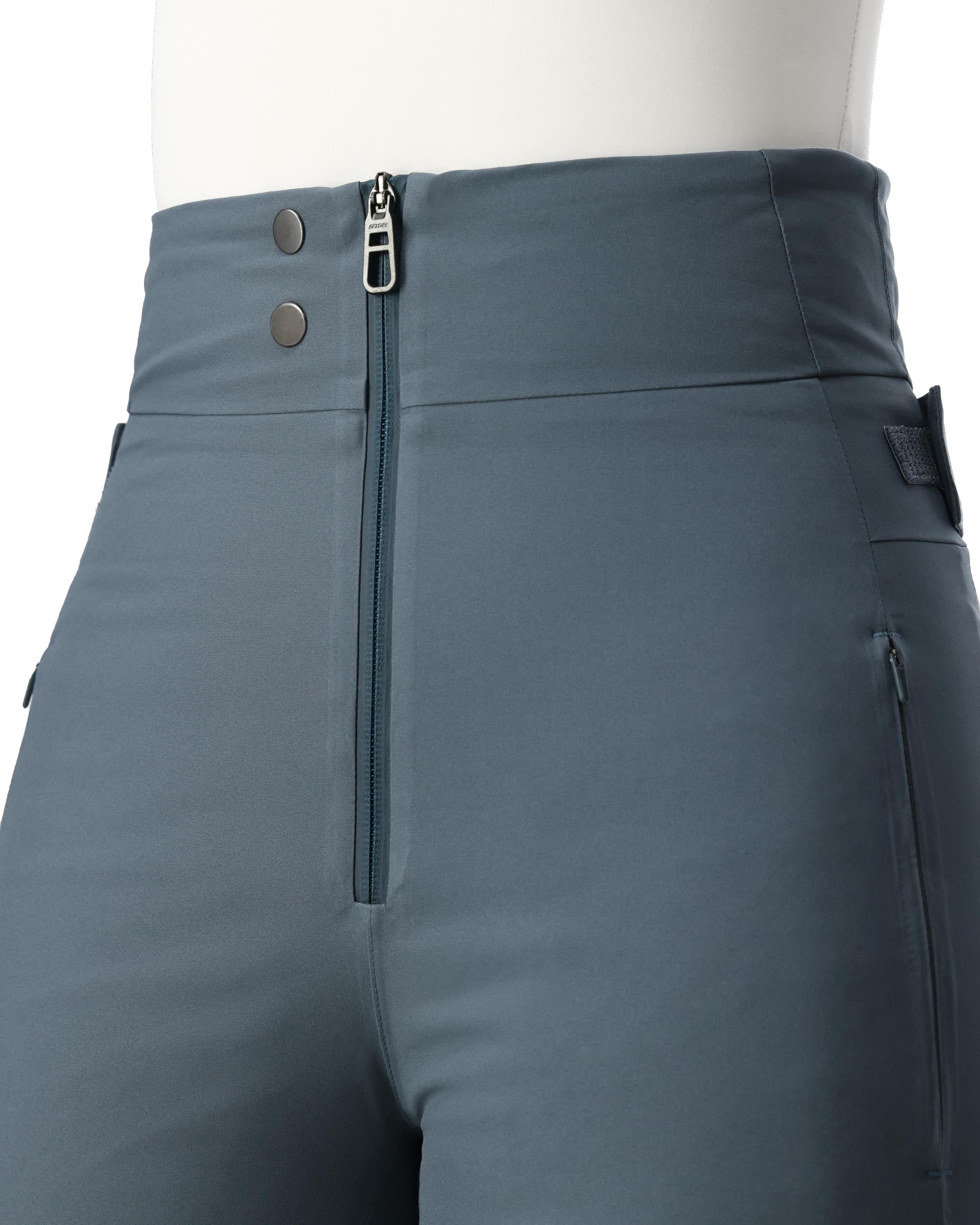 A woman wearing a pair of grey Spyder Women's Fuse Ski Pants that are waterproof, breathable, stretchable, and warm.