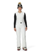 A woman wearing a pair of white Spyder Women's On Piste Ski Bib Pants which are waterproof, breathable, stretchable, and insulated.