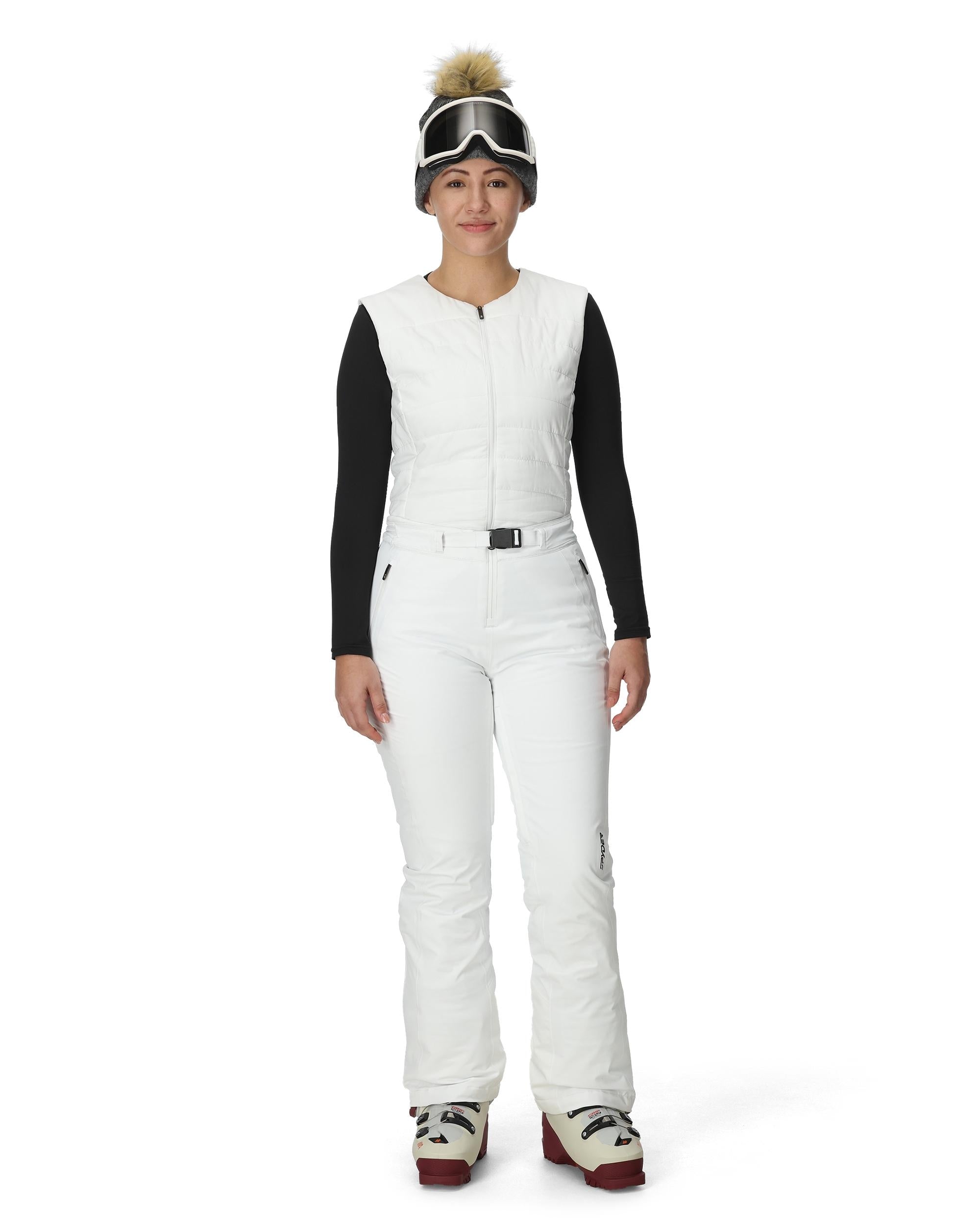 A woman wearing a pair of white Spyder Women's On Piste Ski Bib Pants which are waterproof, breathable, stretchable, and insulated.
