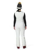 A woman wearing a pair of white Spyder Women's On Piste Ski Bib Pants which are waterproof, breathable, stretchable, and insulated.