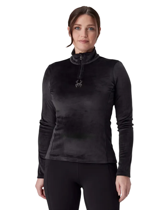 A woman wearing a Spyder Women’s Shimmer Bug 1/2 Zip Sweater featuring stretch velour fleece knit, YKK® reverse coil center front zipper, T-neck collar, and jeweled crystal logo.