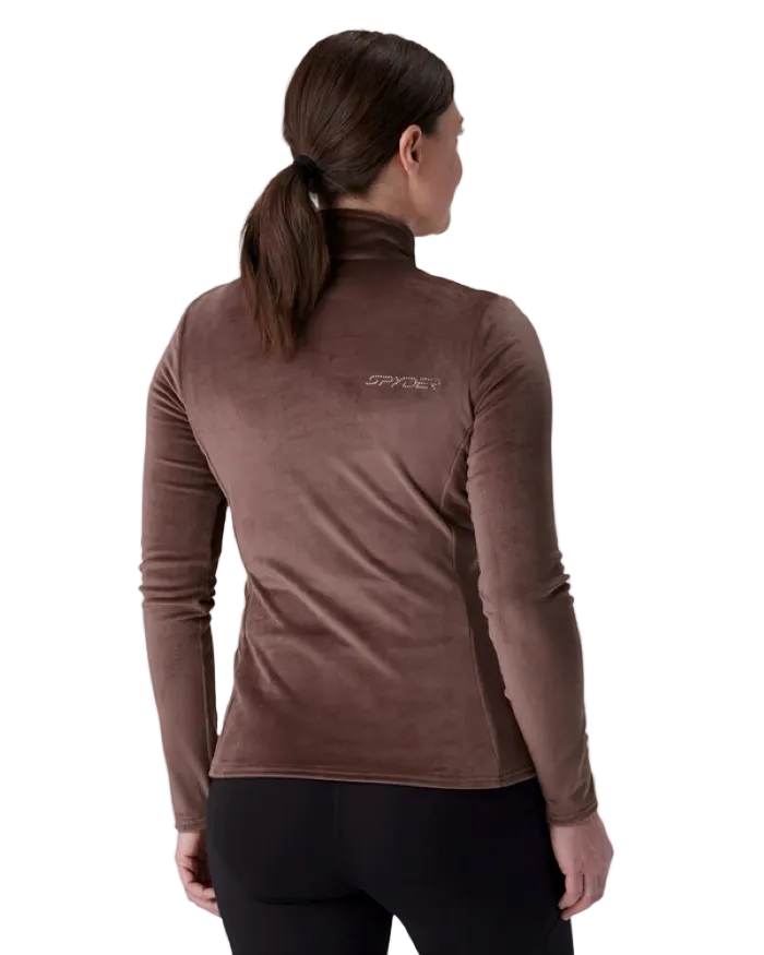 A woman wearing a Spyder Women’s Shimmer Bug 1/2 Zip Sweater featuring stretch velour fleece knit, YKK® reverse coil center front zipper, T-neck collar, and jeweled crystal logo.