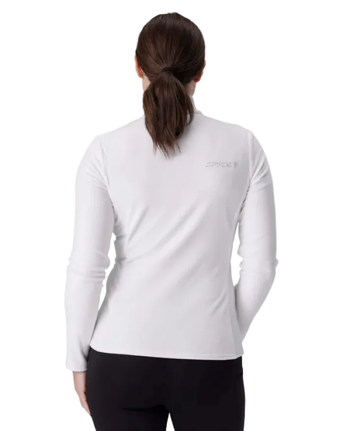 A woman wearing a Spyder Women’s Shimmer Bug 1/2 Zip Sweater featuring stretch velour fleece knit, YKK® reverse coil center front zipper, T-neck collar, and jeweled crystal logo.
