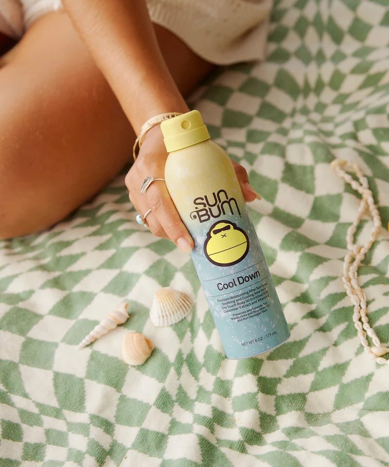 A woman holding a Sun Bum Cool Down after sun spray bottle