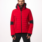 A man wearing a red and black Toni Sailer Men's Matti Ski Jacket made from premium fabrics and insulation that is waterproof, breathable, stretchable, insulated, and fashionable.