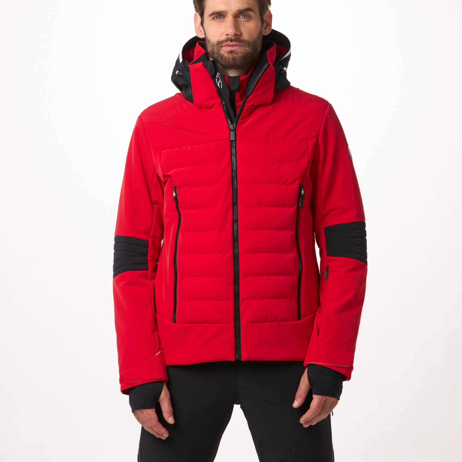 A man wearing a red and black Toni Sailer Men's Matti Ski Jacket made from premium fabrics and insulation that is waterproof, breathable, stretchable, insulated, and fashionable.