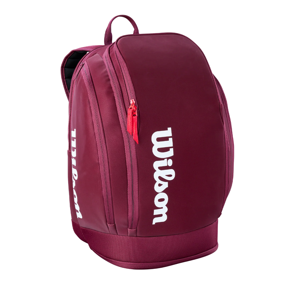A Wilson Defyer Tennis Backpack showing water-resistant polyester exterior, rear locking 2-racquet compartment, ventilated bottom shoe pocket, thermoguard side pocket, and padded mesh shoulder straps.
