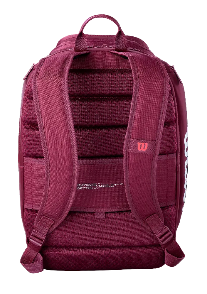 A Wilson Defyer Tennis Backpack showing water-resistant polyester exterior, rear locking 2-racquet compartment, ventilated bottom shoe pocket, thermoguard side pocket, and padded mesh shoulder straps.